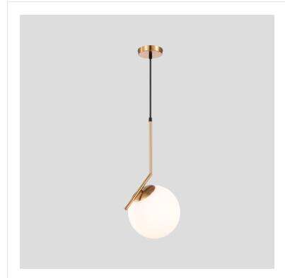 Modern Nordic glass ball pendant light with gold accents hanging in a dining room